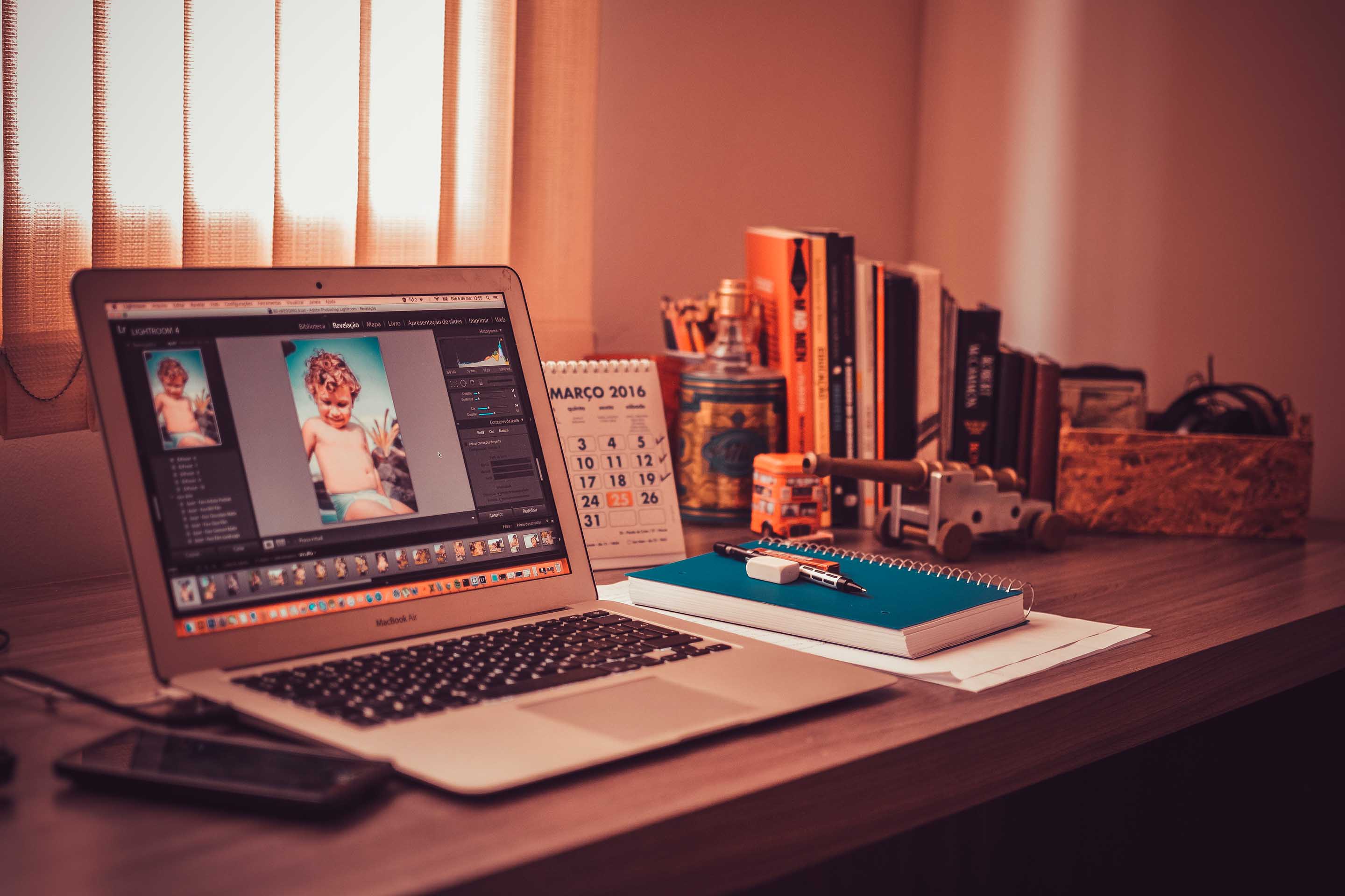 Schreibtisch mit Laptop, Notebook, Büchern und Handy darauf