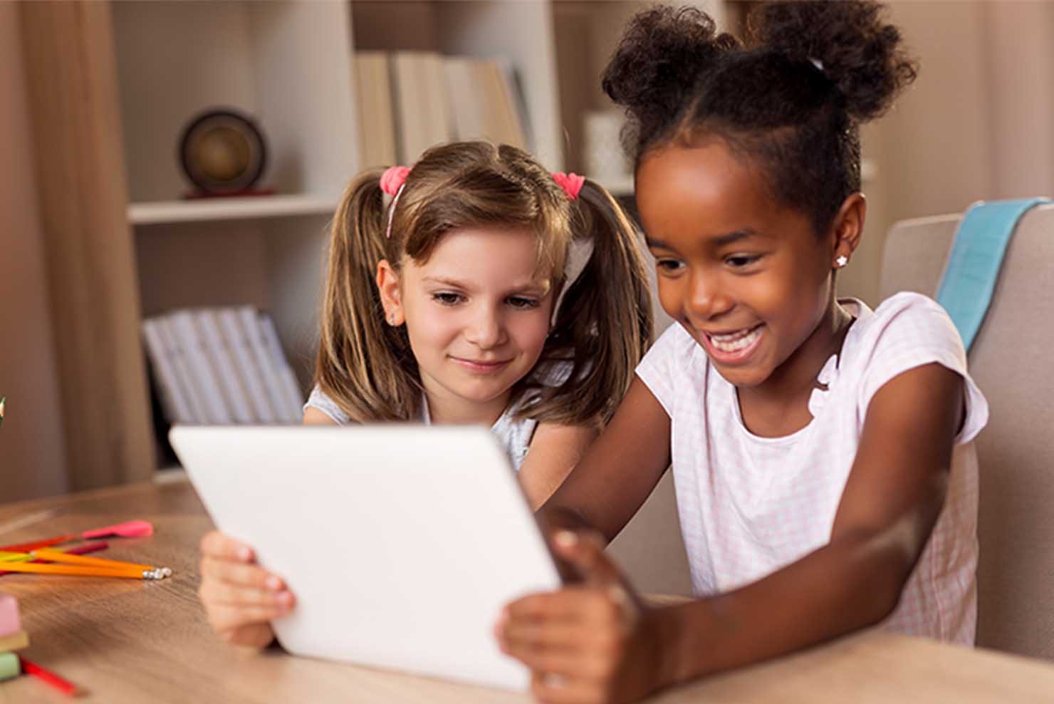 deux filles souriantes et regardant une tablette