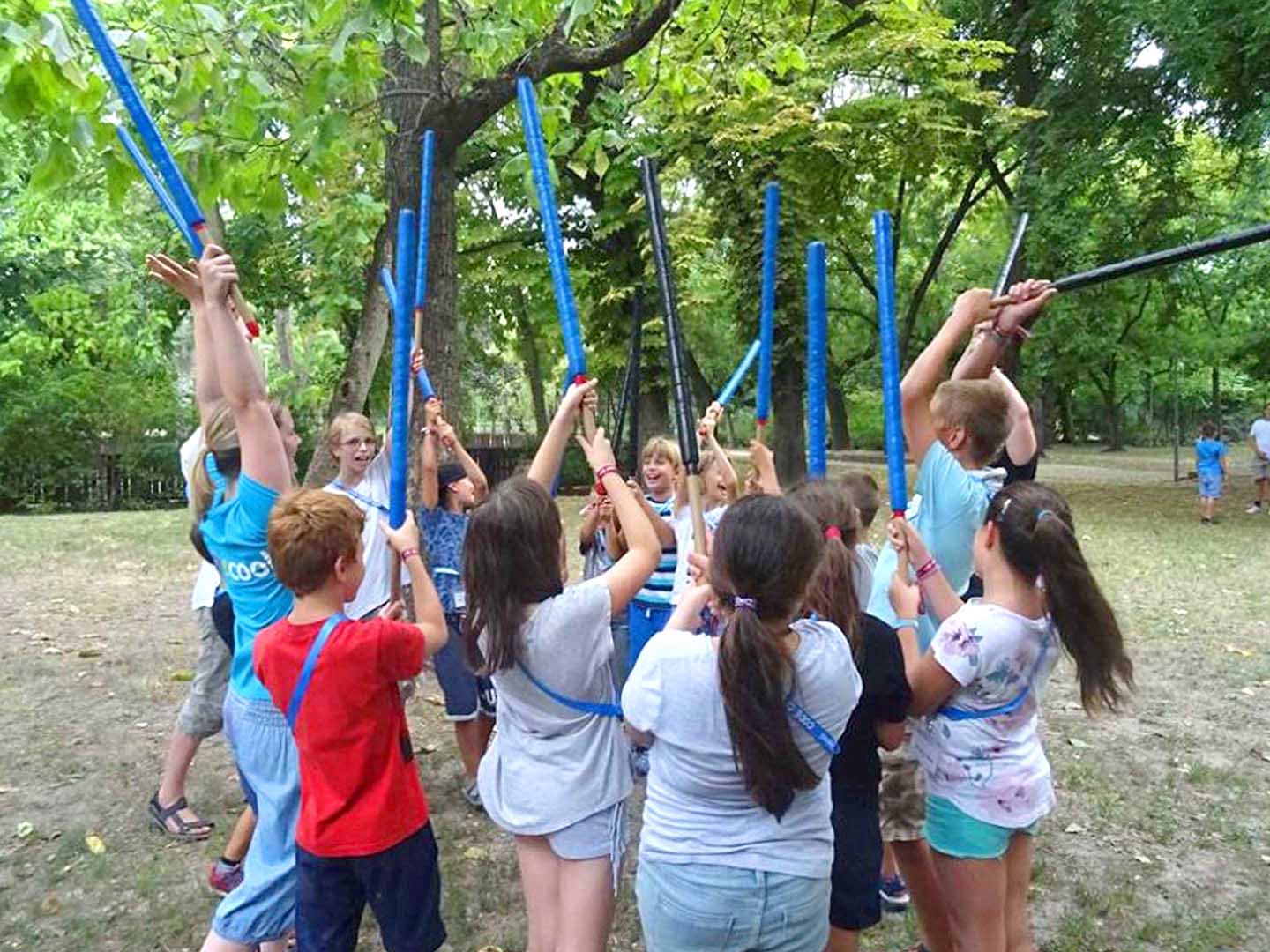 Kinder in einem Camp spielen ein Spiel mit blauen Stöcken