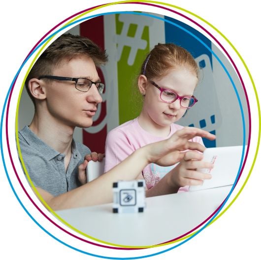 little girl in pink next to a teen boy in gray t-shirt looking at a tablet