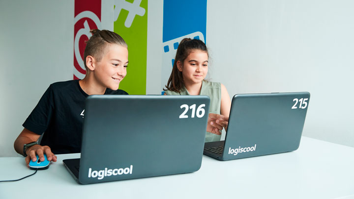 boy and girl sitting next to each other looking at laptops